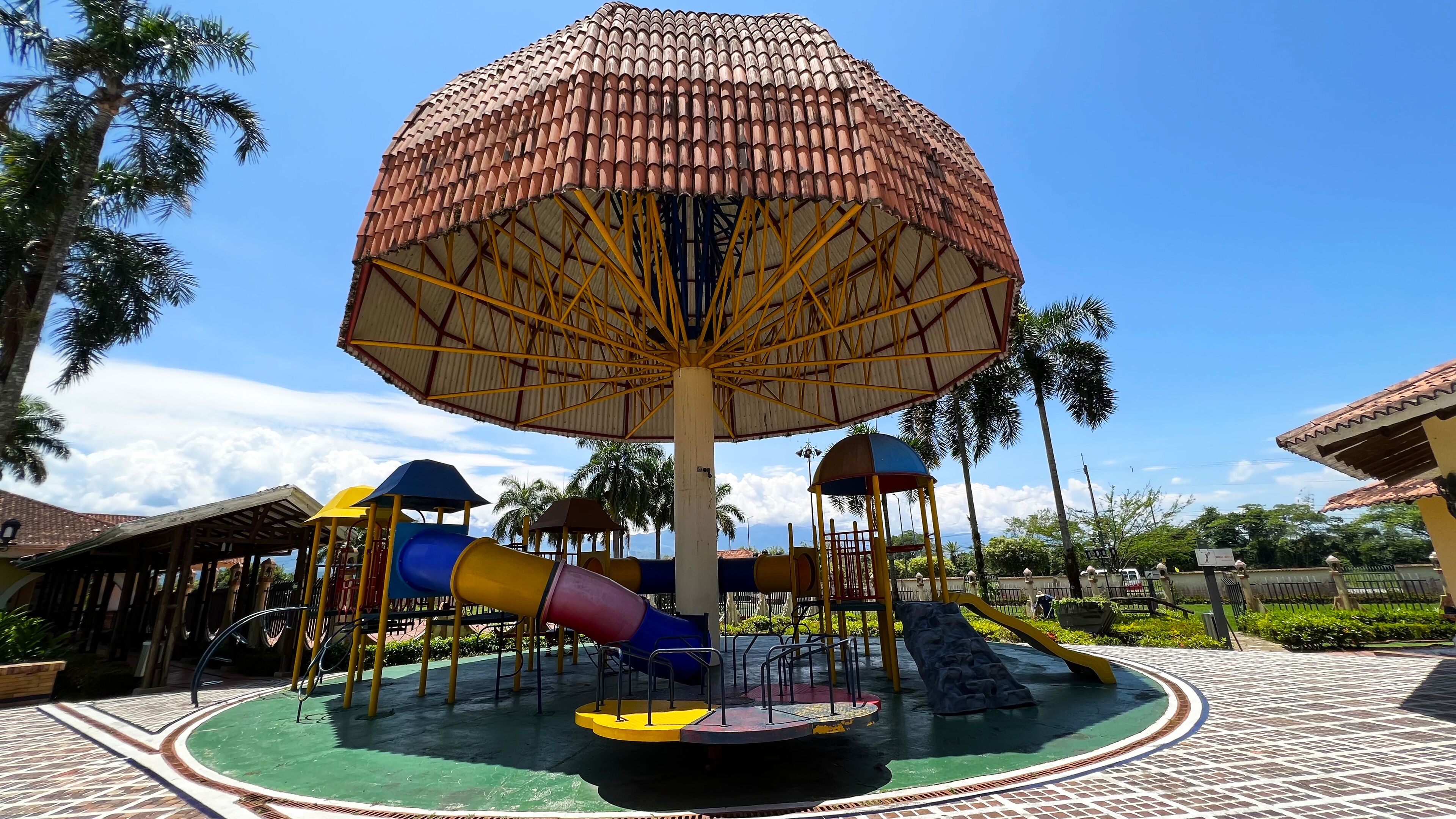 A playground with a large umbrella structure, slides, and a circular play area.