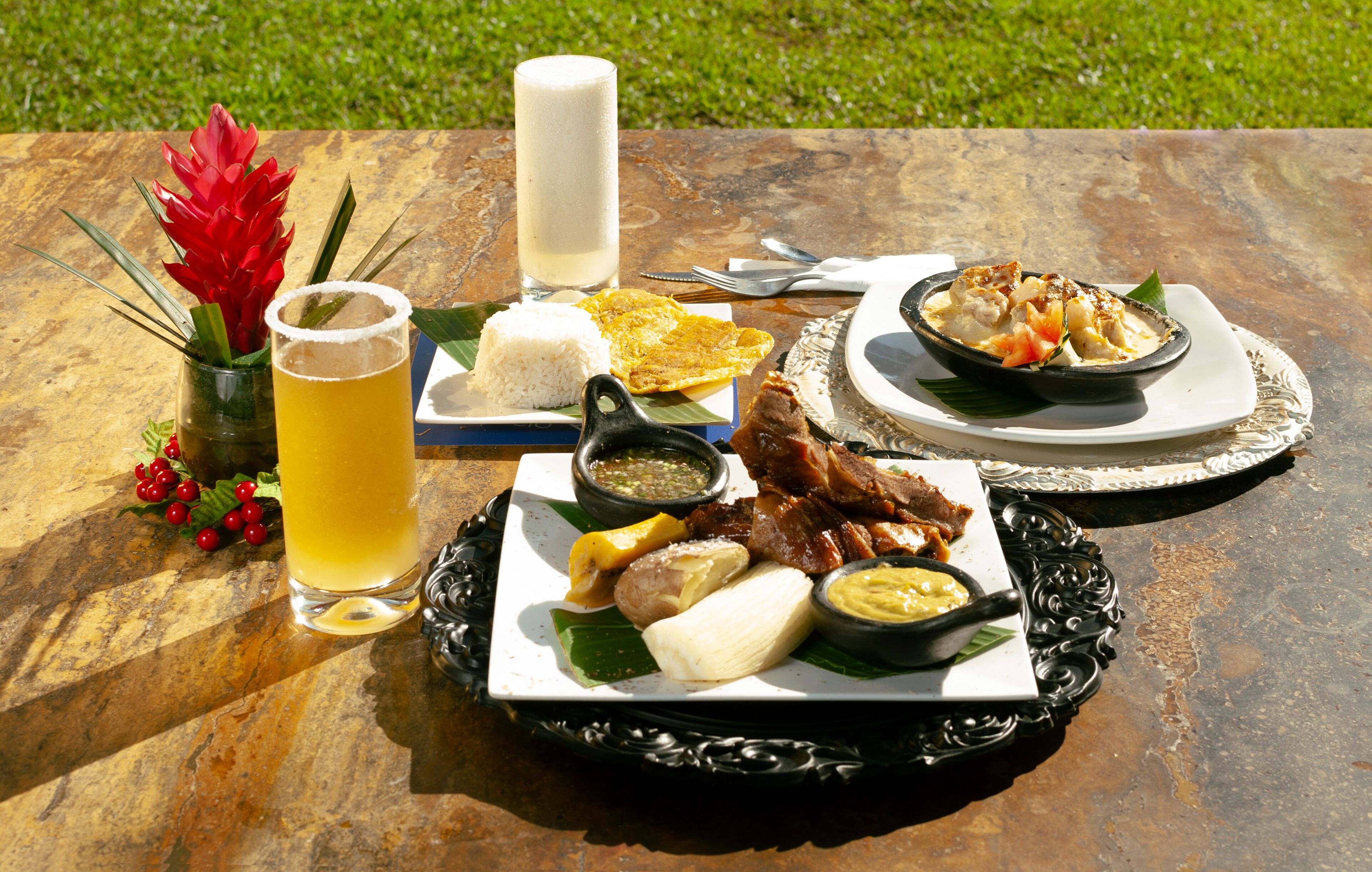 A meal with rice, meat, and a drink on a table outdoors.