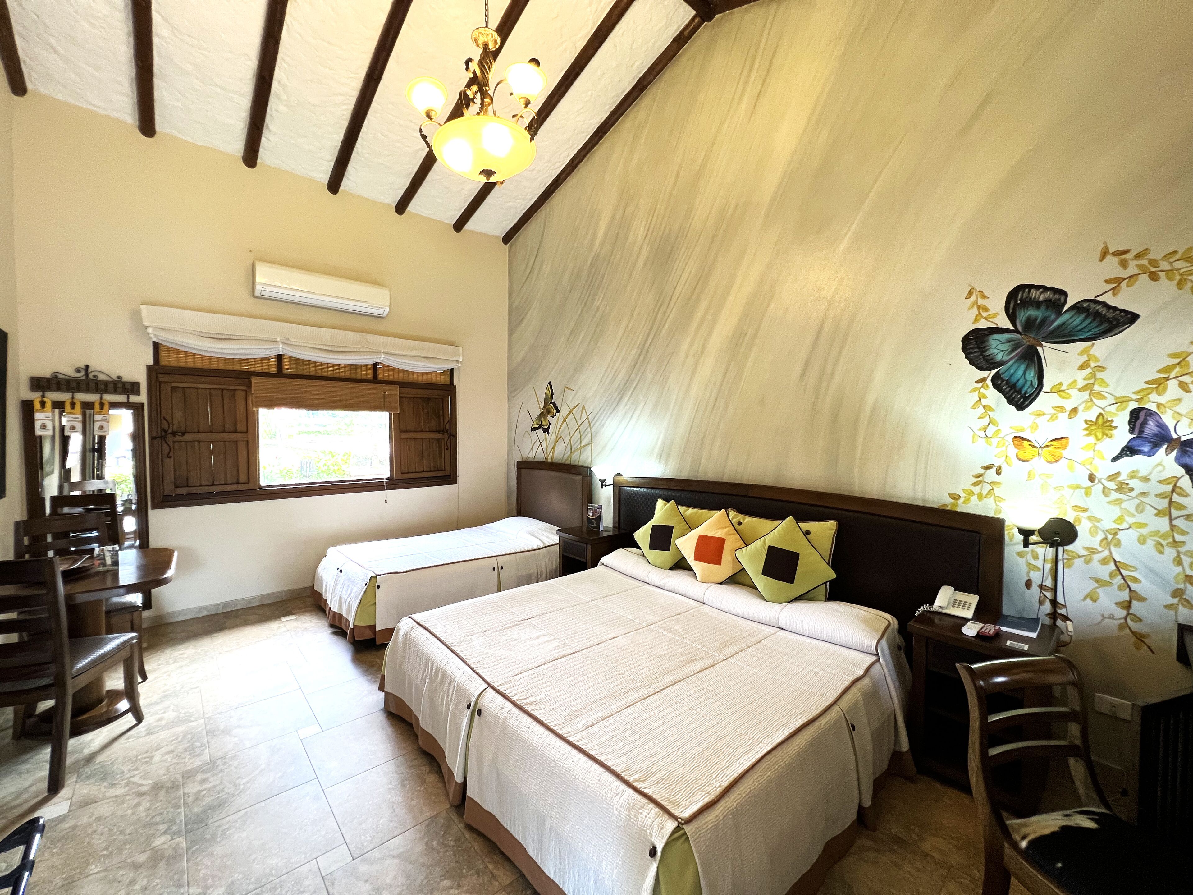 Habitación de hotel con dos camas, un comedor y un candelabro.
