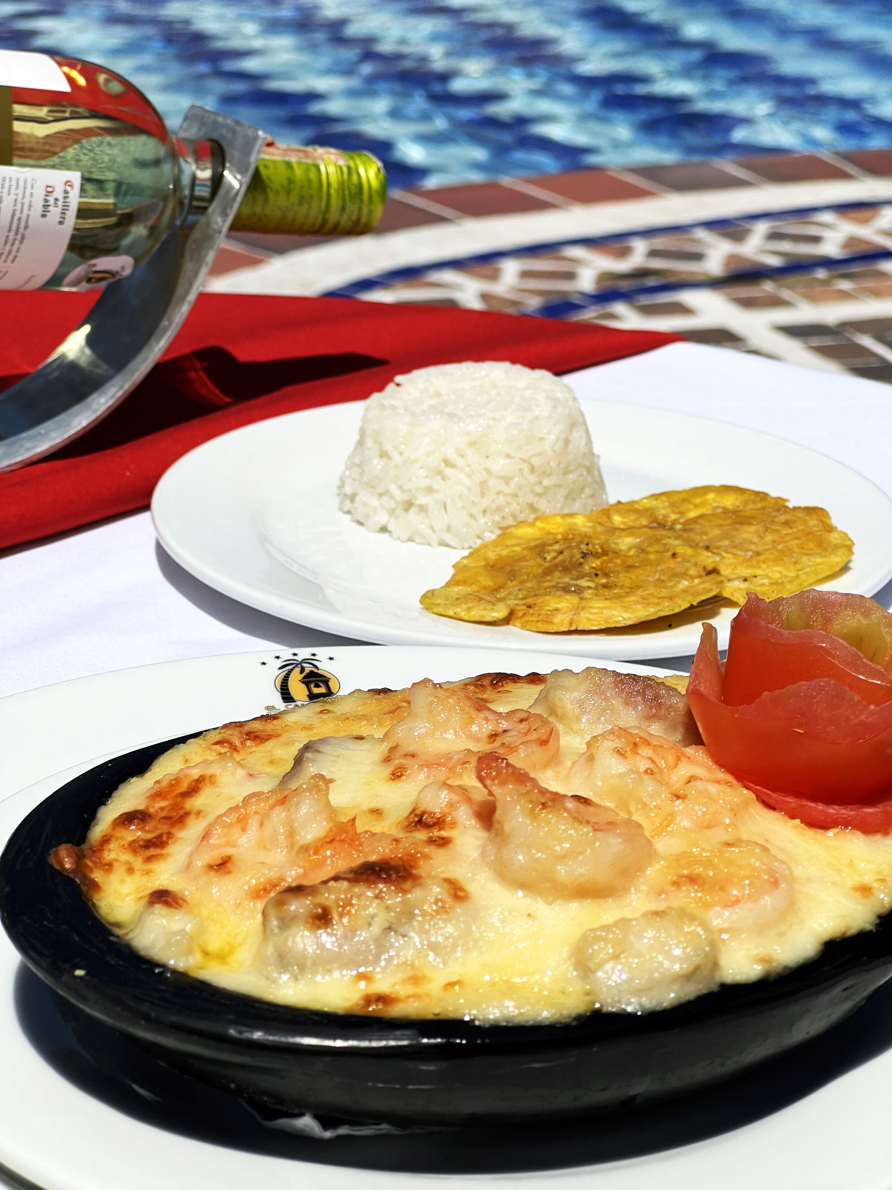 Eine Mahlzeit mit Reis, gebratenen Kochbananen und einem Fischgericht auf einem Tisch mit Fliesenboden.