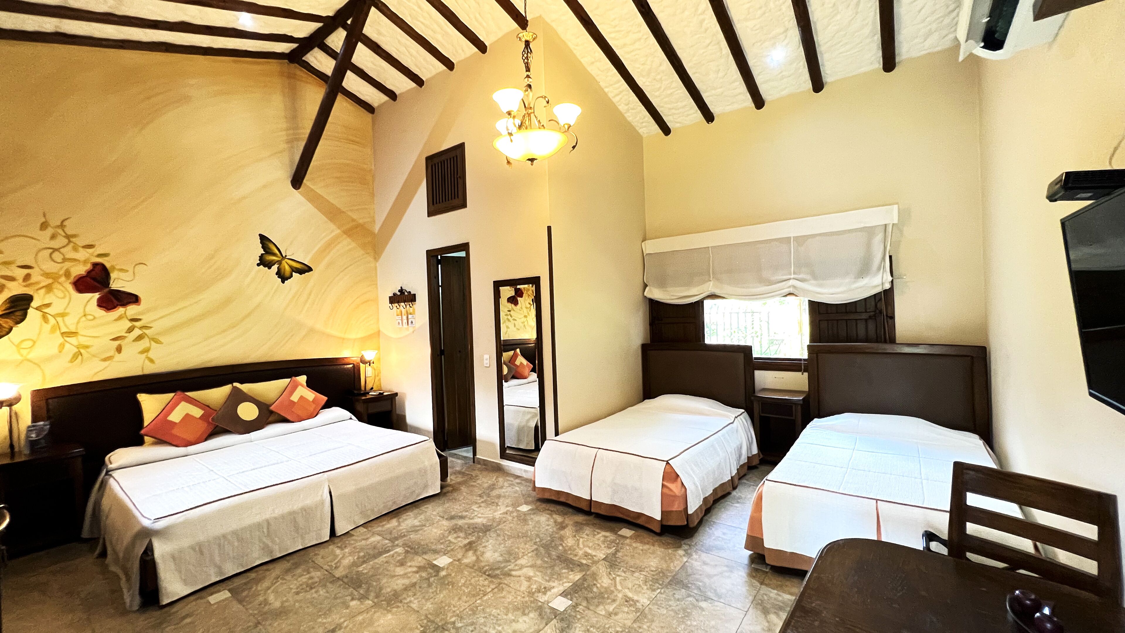 Een kamer met twee bedden, een kroonluchter, een spiegel en een raam met gordijnen.