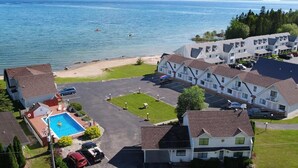 A coastal hotel with a swimming pool, a parking lot, and a view of the sea. - Bridge View Motel & Condo's (Mackinaw City)