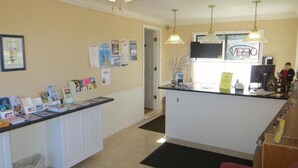 A reception area with a counter, informational posters, and a television. - Bridge View Motel & Condo's (Mackinaw City)