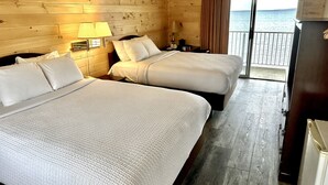 A hotel room with two beds, wooden walls, a balcony with a view of the sea, and a refrigerator. - Bridge View Motel & Condo's (Mackinaw City)