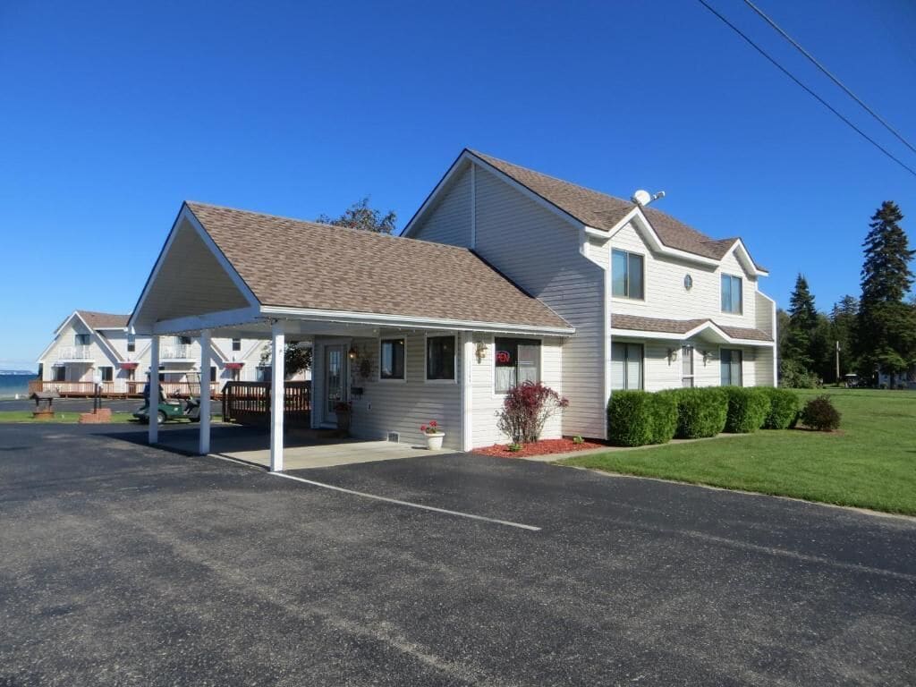 A two-story motel with a covered parking area and a grassy lawn.