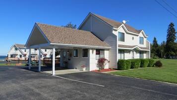 A two-story motel with a covered parking area and a grassy lawn.
