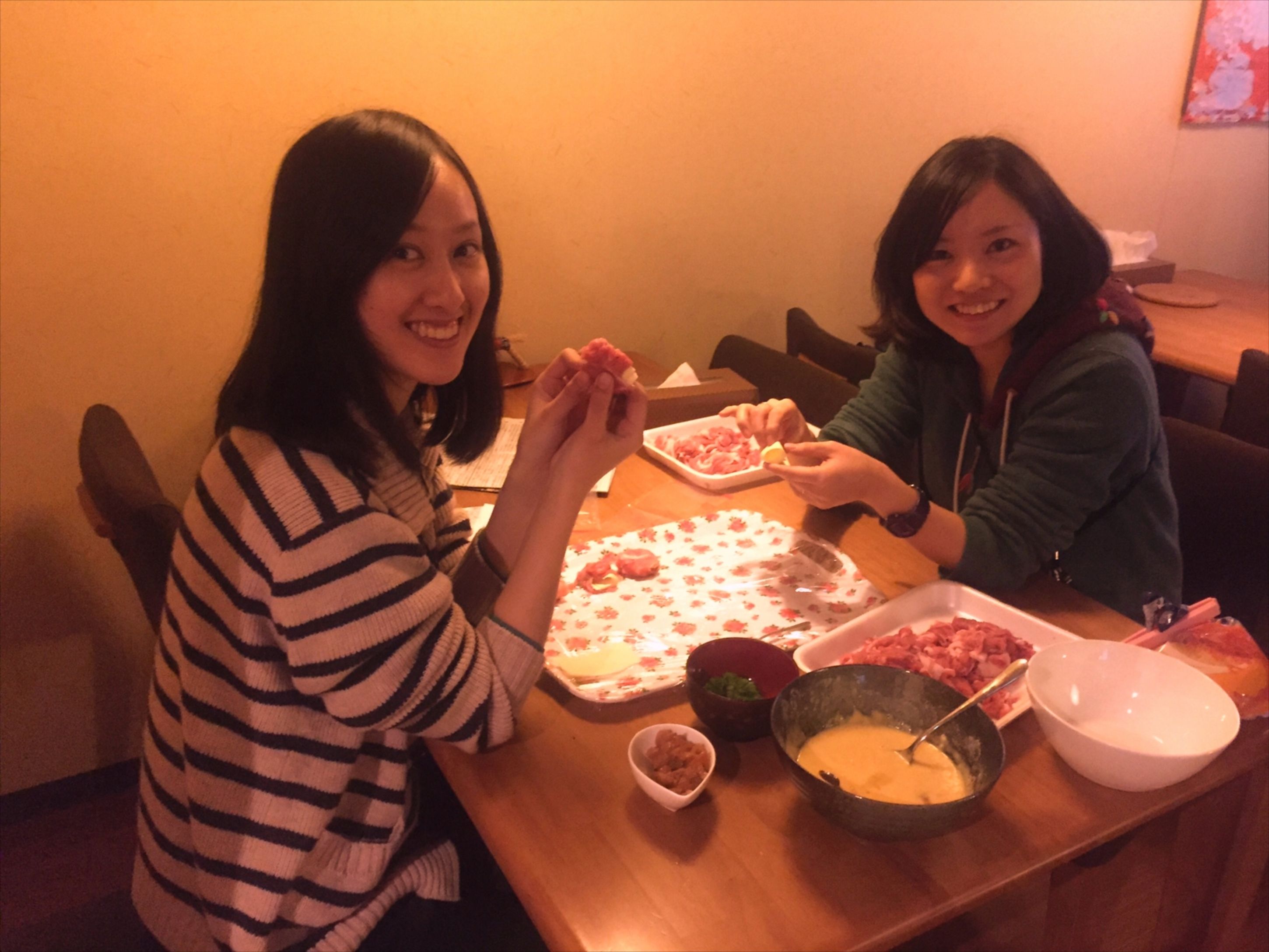 Two people sitting at a table with food items and a bowl of soup.