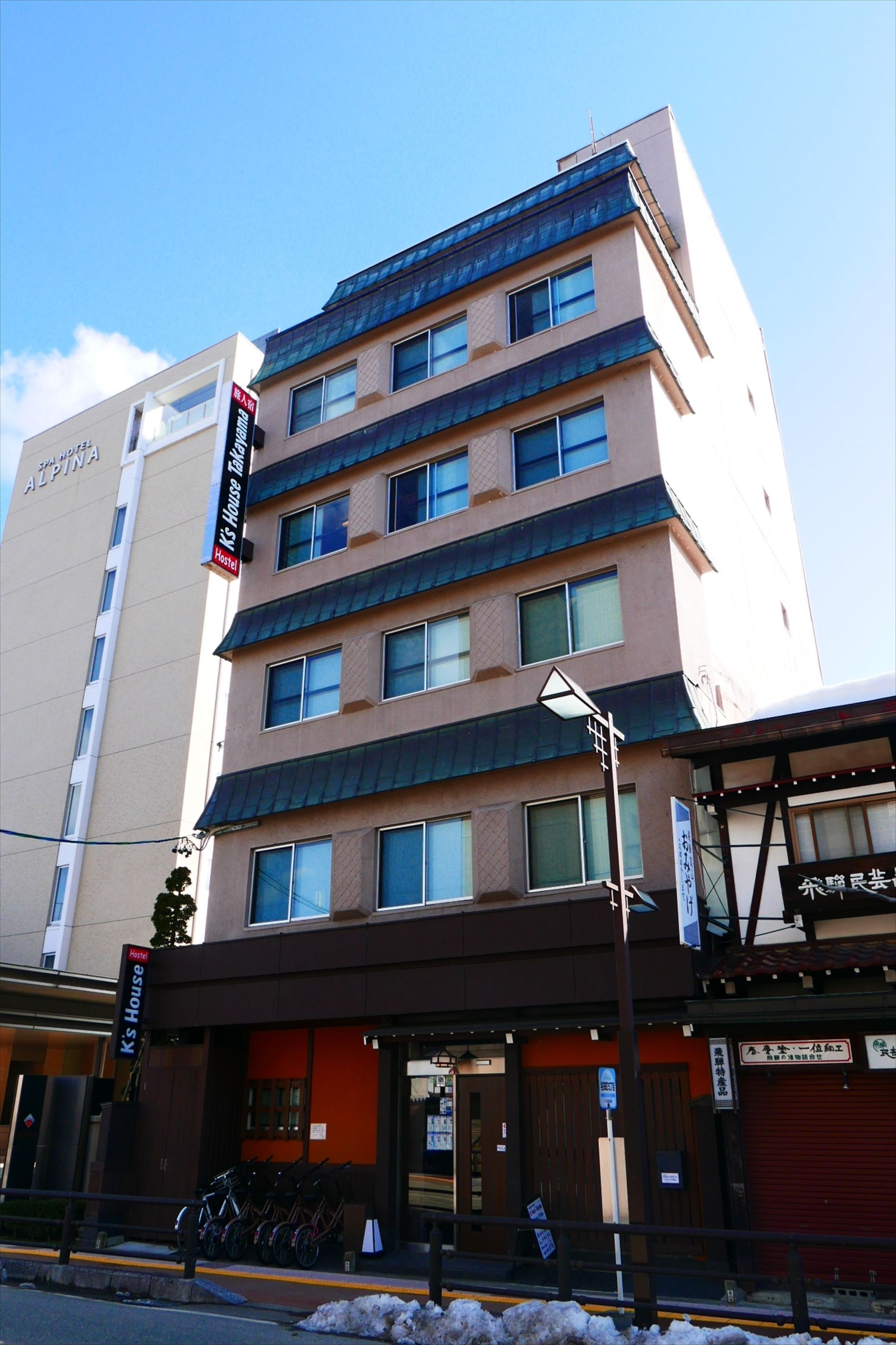 A multi-story hotel with a modern design, featuring a prominent 'Hotel' sign and a visible entrance with a red awning.