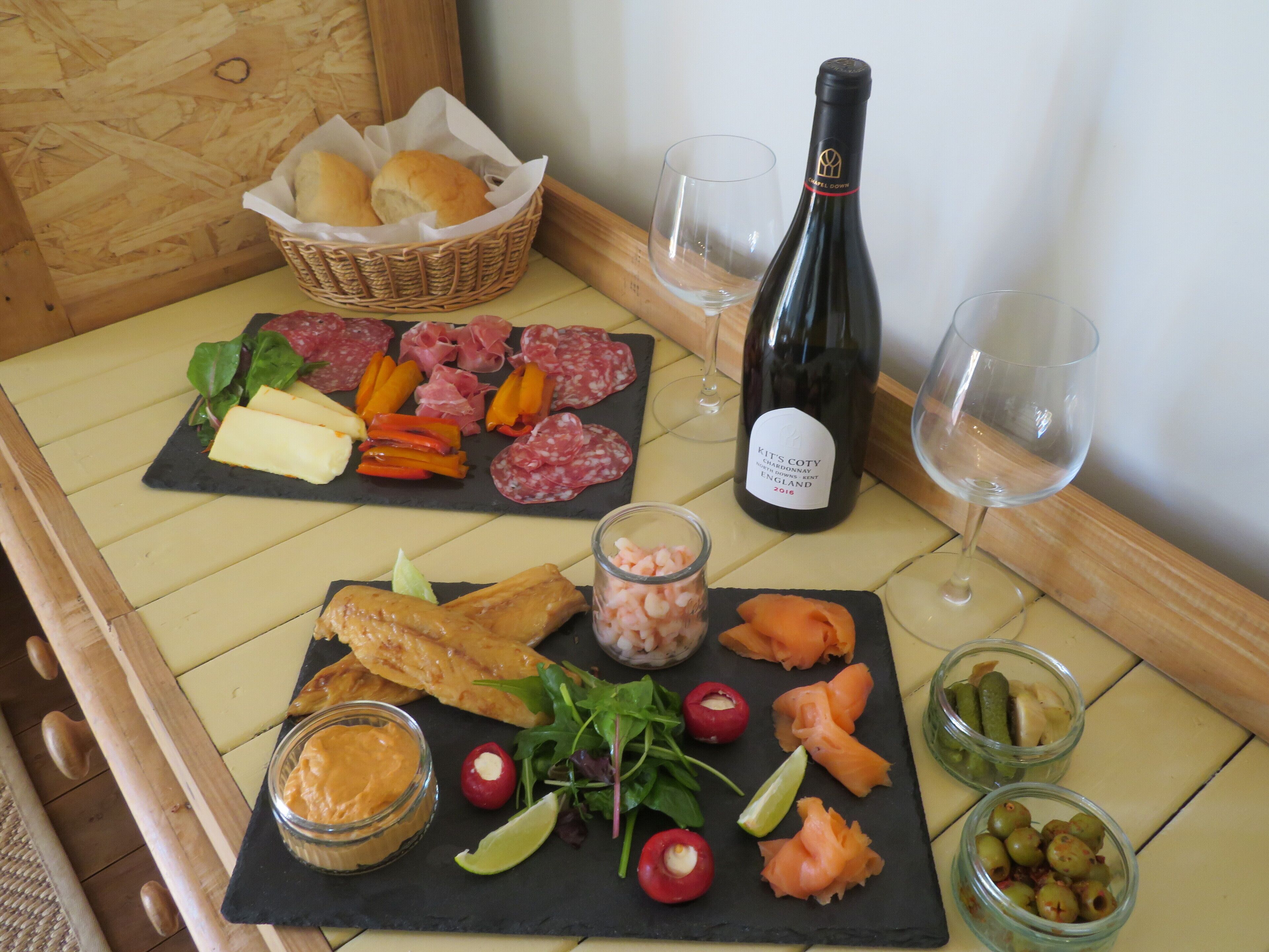 A table with a variety of food items and a bottle of wine.