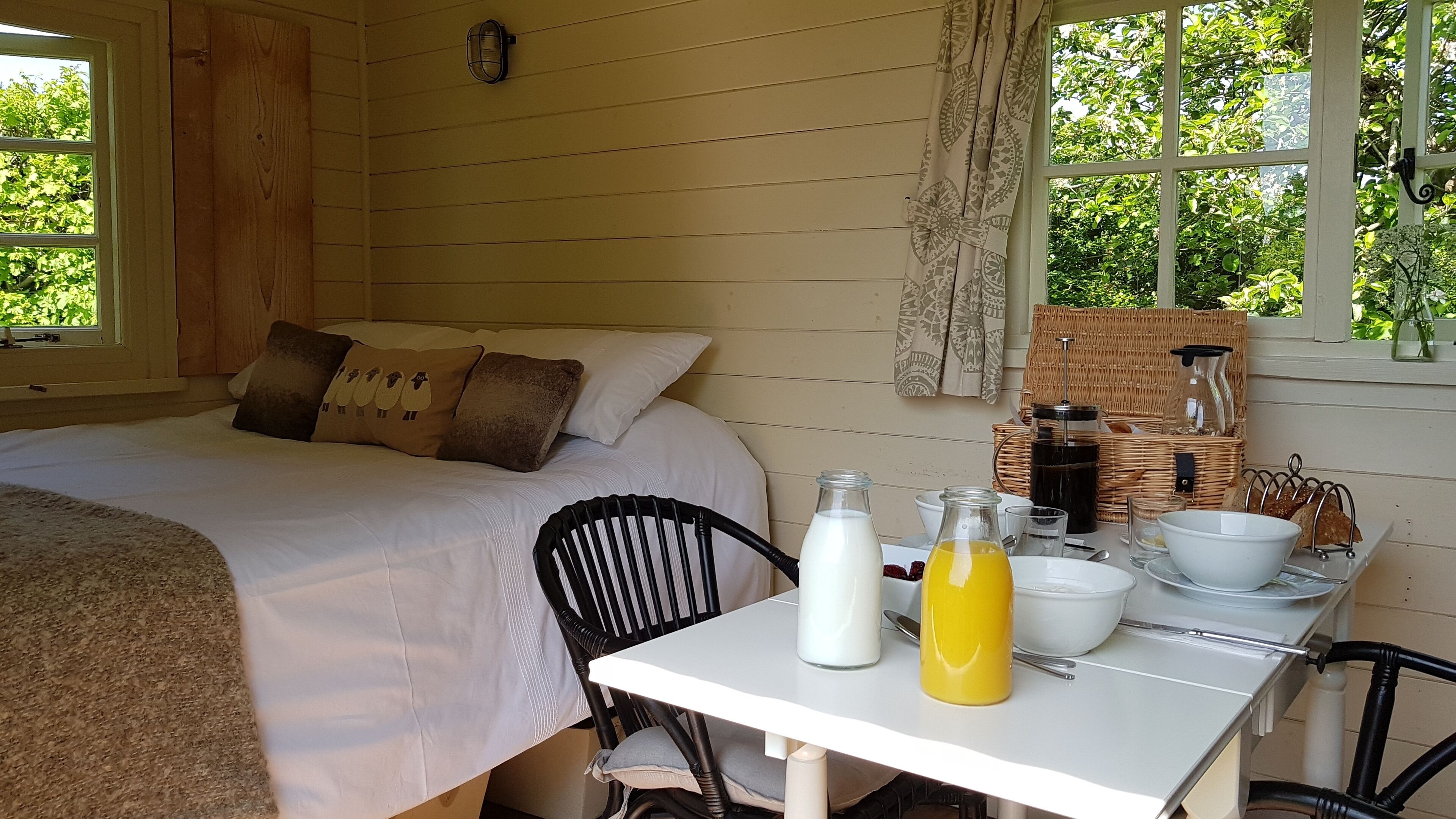 Una habitación acogedora con una cama, una mesa con alimentos para el desayuno y vistas al exterior.