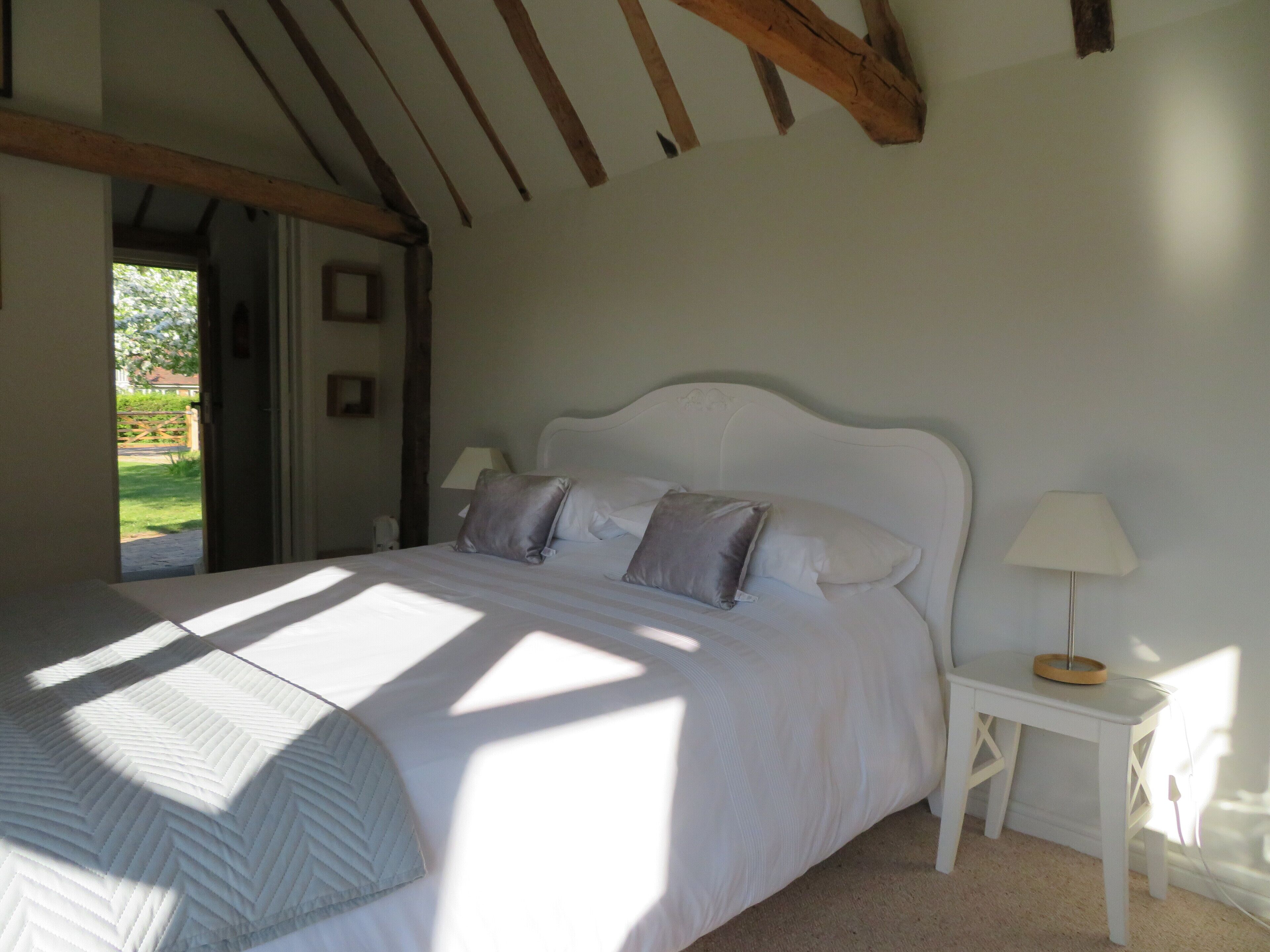 A bedroom with a bed, bedside tables, and a view of the outdoors.