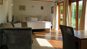 Une chambre à coucher avec un lit, une chaise, une table et une fenêtre avec des rideaux.