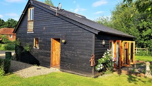 Une maison en bois noire, avec un toit en pente, une porte en bois et une fenêtre.