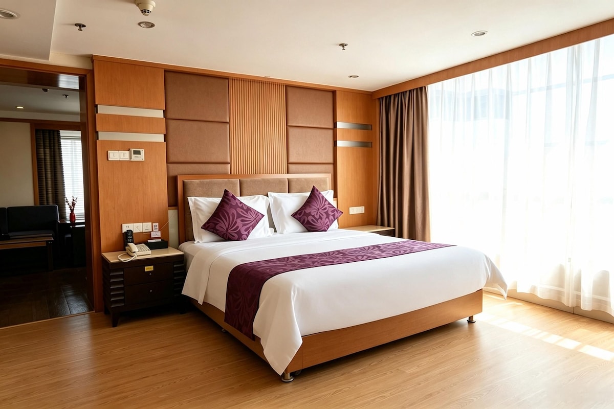 A hotel room with a large bed, wooden headboard, and a view of the outdoors through a window.