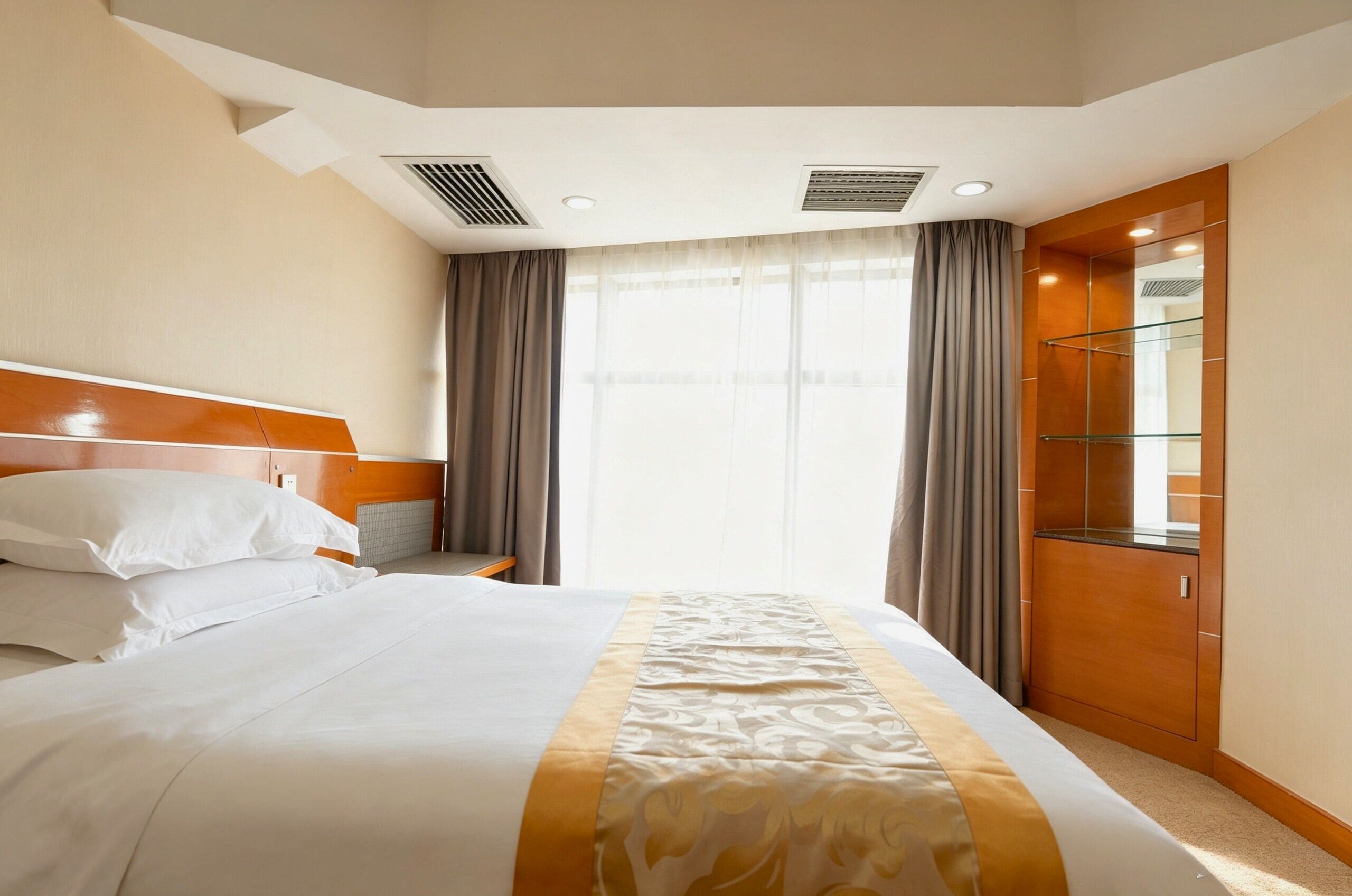 Ein Hotelzimmer mit Bett, Nachttisch, Spiegel und einem Fenster mit Vorhängen.