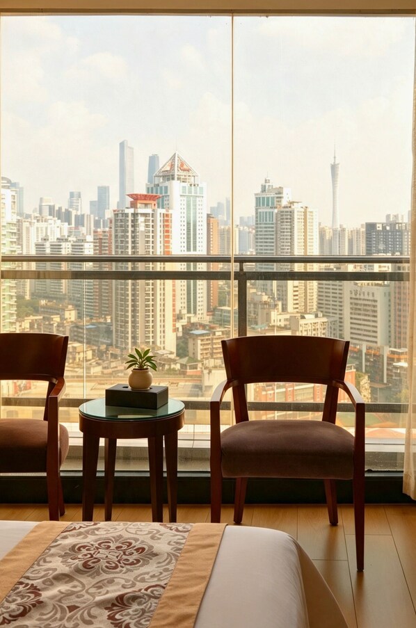 Una habitación con un ventanal grande que da a un paisaje urbano, dos sillas de madera, una mesita con una planta y una cama con un edredón estampado.