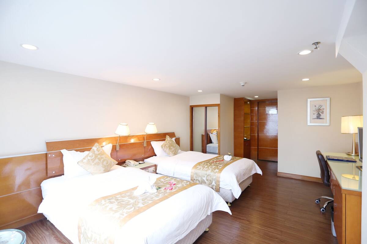 Ein Hotelzimmer mit zwei Betten, einem Schreibtisch und einem Stuhl.