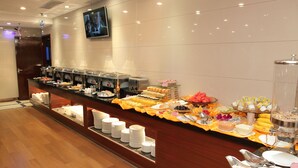 Un buffet proposant une variété de plats et d’ustensiles, un téléviseur fixé au mur et un plancher en bois.