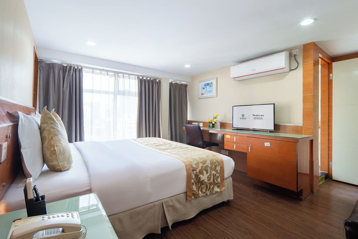 Ein Hotelzimmer mit einem Bett, einem Schreibtisch, einem Stuhl, einem Telefon und einer Klimaanlage.