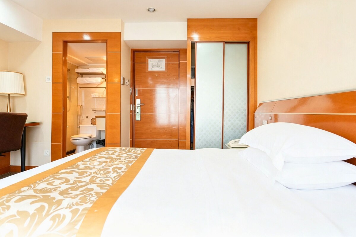 Une chambre d’hôtel comprenant un lit, une table de chevet, une lampe, une chaise, une armoire et une salle de bain.