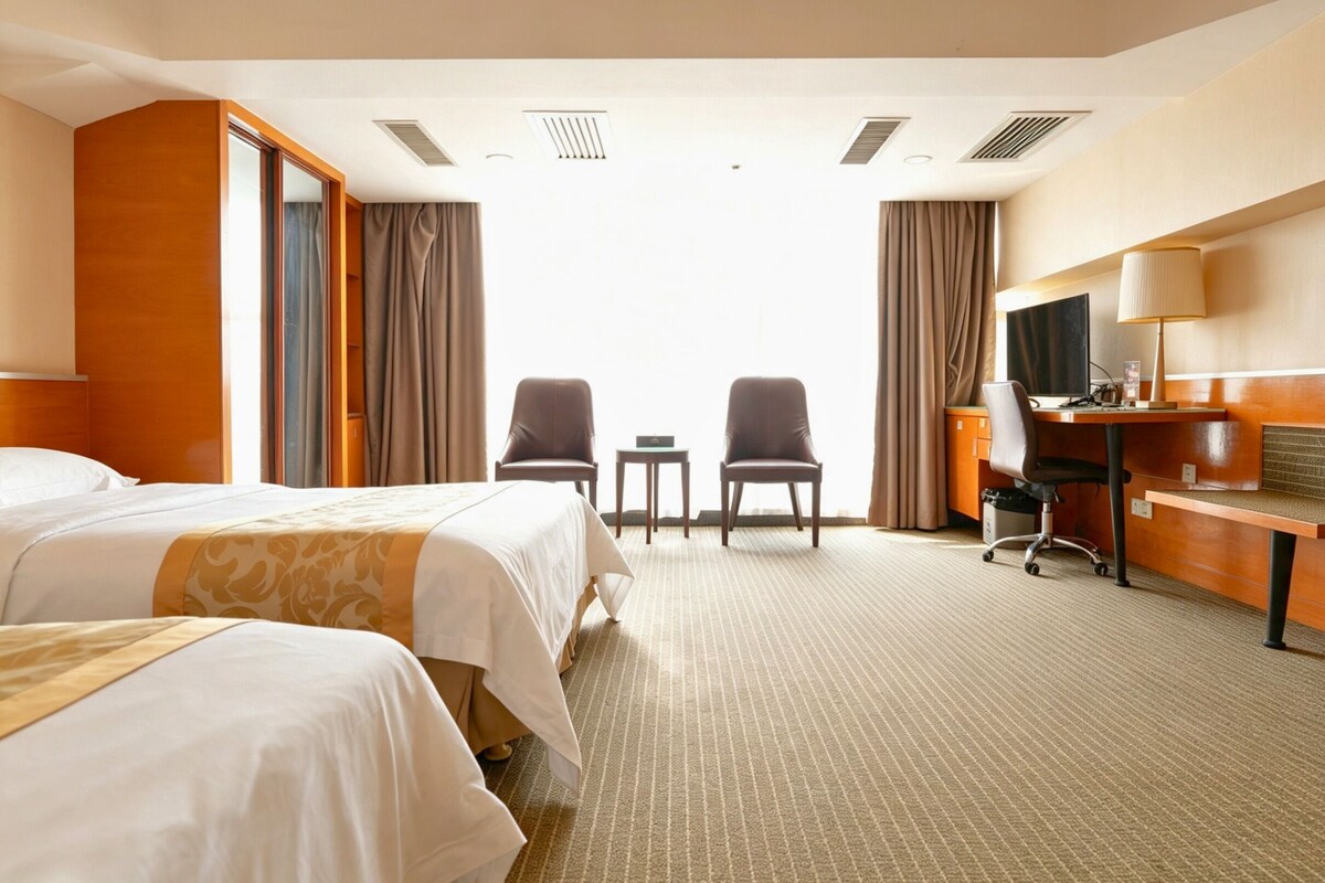 Ein Hotelzimmer mit zwei Betten, einem Schreibtisch mit Stuhl, einem Fernseher und Blick ins Freie.