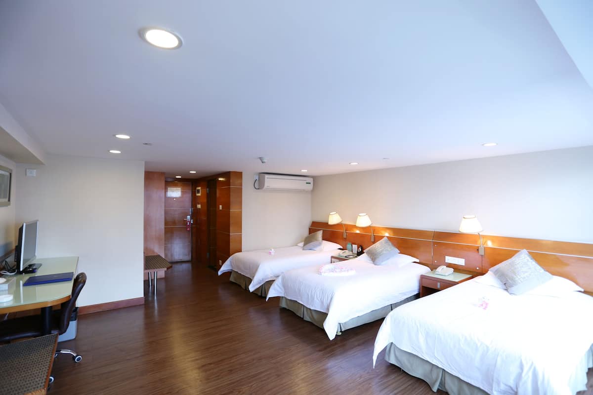 Ein Hotelzimmer mit zwei Betten, einem Schreibtisch mit Computer und einem Stuhl.