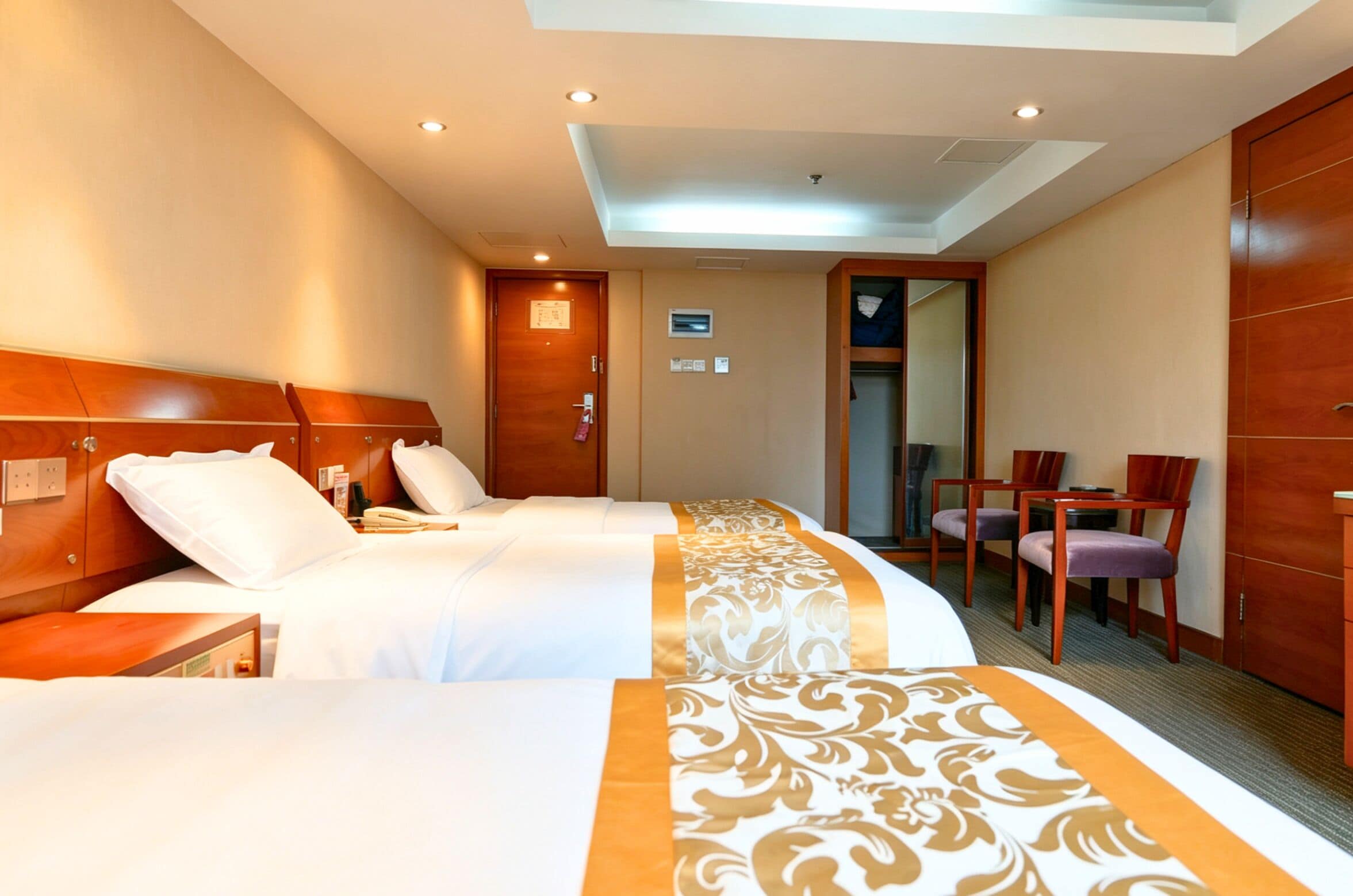 Een hotelkamer met twee bedden, een bureau en een stoel.