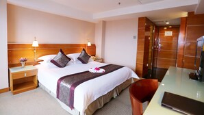 A hotel room with a large bed, bedside lamps, a desk, and a chair.