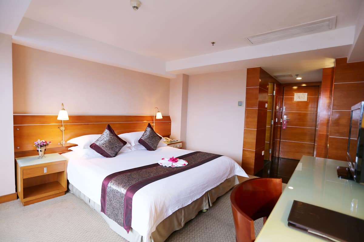 Ein Hotelzimmer mit einem großen Bett, Nachttischlampen, einem Schreibtisch und einem Stuhl.
