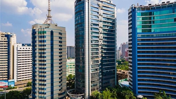 A modern urban skyline with high-rise buildings, including a hotel with a prominent vertical sign.