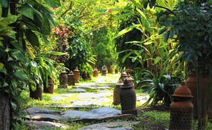 Um caminho de jardim com lajes de pedra e vasos de barro tradicionais.
