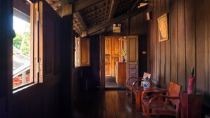 A wooden interior with a wooden bench, a door leading to another room, and a window with natural light.