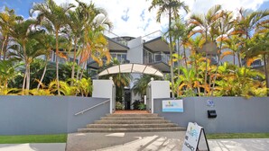 A hotel entrance with a sign indicating no vacancy, surrounded by palm trees and a modern building with balconies. - Dockside Mooloolaba (Mooloolaba)