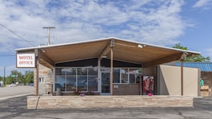 A motel office with a stone facade, large windows, and a Coca-Cola vending machine.