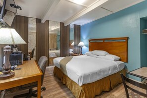 A hotel room with a bed, a desk, a chair, a lamp, and a mirror. - Budget Inn Boise (Boise)