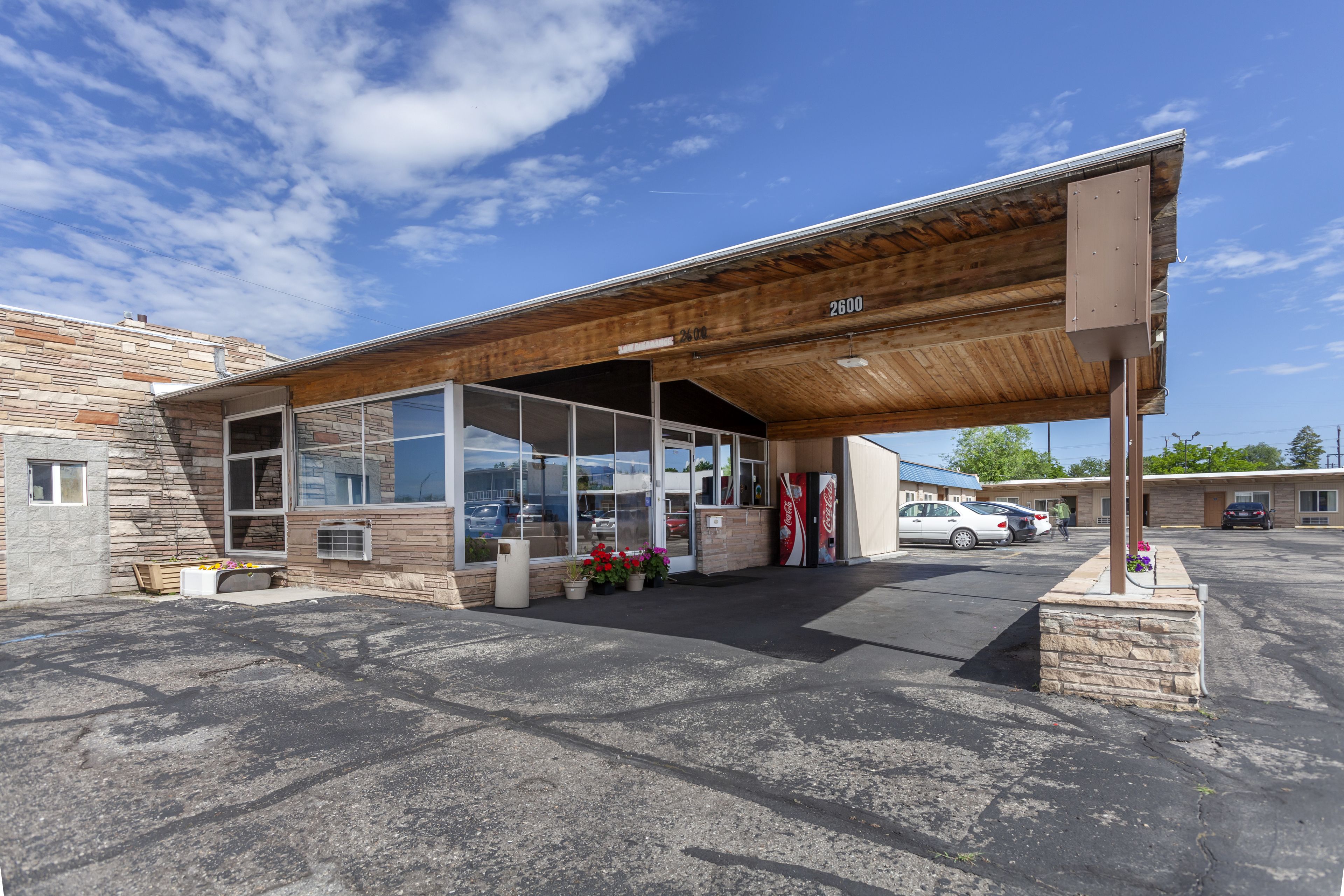 Un bâtiment avec une façade en pierre, une entrée couverte et une enseigne Coca-Cola.