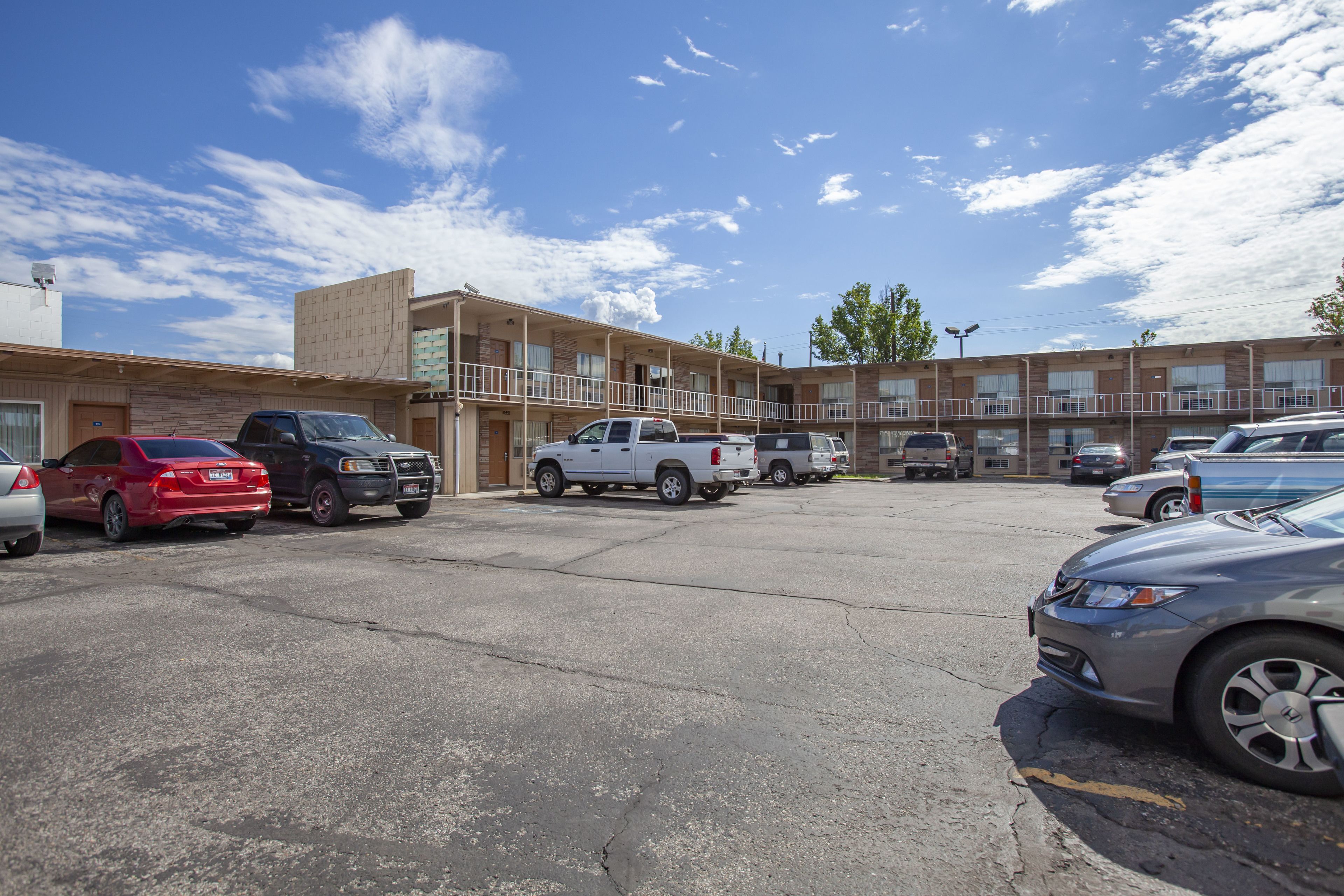 A parking lot with several cars and a motel building in the background.