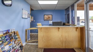 A reception desk with a wooden counter, a clock, and a framed picture on the wall.