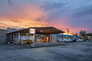 A motel with a Coca-Cola sign, a covered front desk, and several parked cars.