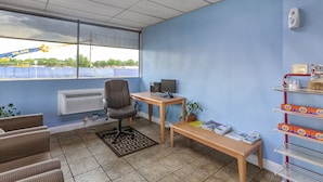 A room with a desk, chair, and shelves with Tide products.