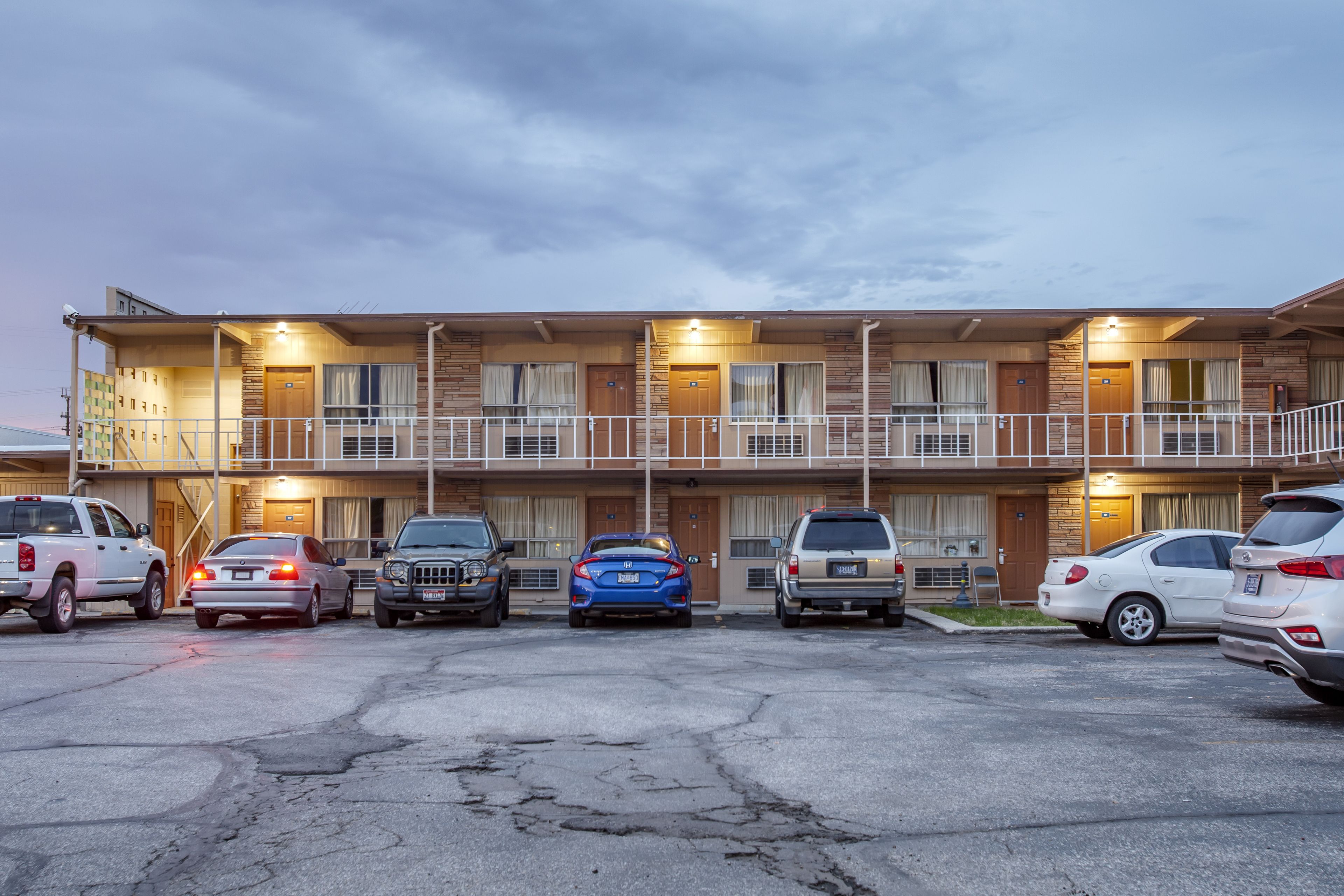 A motel with a two-story structure, multiple parking spaces, and a balcony on the upper floor.