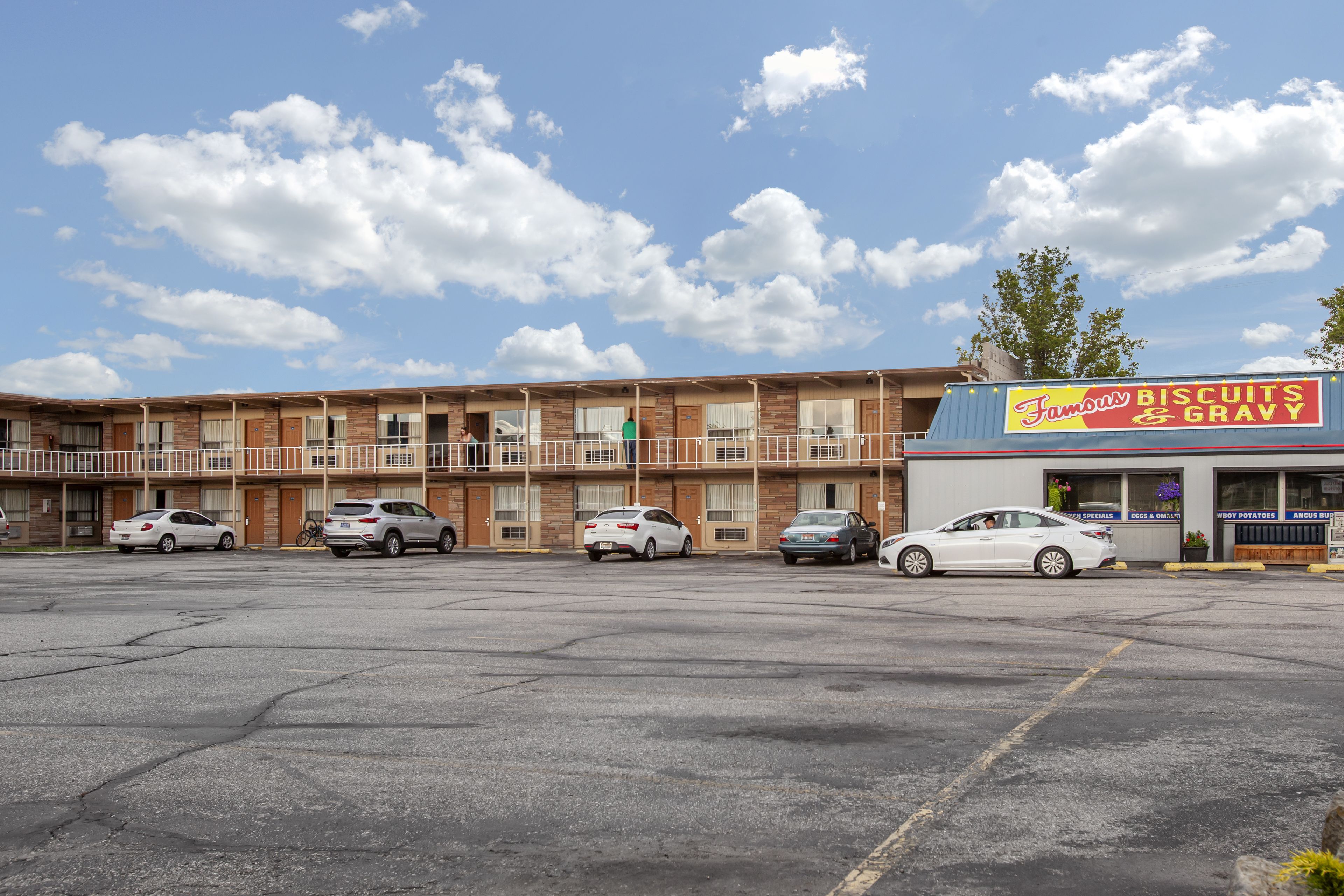 Un motel con diversi piani, un parcheggio e un ristorante chiamato 'Famous Biscuits & Gravy'.