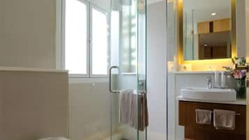 Un baño moderno con ducha de mampara de vidrio, tocador con espejo y inodoro.