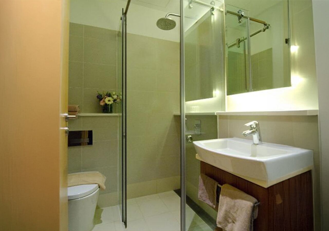 Un baño con ducha de vidrio, un lavamanos blanco y un inodoro.