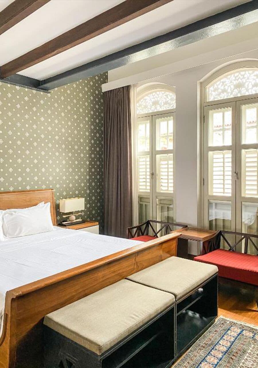 A hotel room with a bed, a desk, a chair, and a window with curtains.