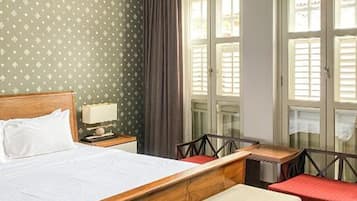 A hotel room with a bed, a desk, a chair, and a window with curtains.
