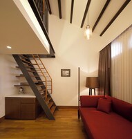 A modern living room with a wooden staircase, a red sofa, and a lamp.