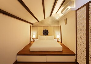 A bedroom with a wooden headboard, two bedside lamps, and a decorative wall panel. - The Sultan (Singapore)