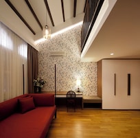 A modern interior with a red sofa, a dining table with chairs, and a staircase.