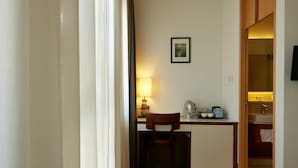 A compact room with a desk, chair, and a small kitchenette area.